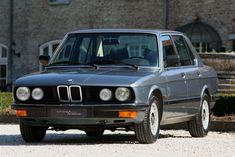 an old bmw is parked in front of a house