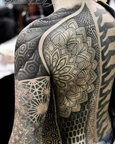 the back of a man's body with intricate tattoos on his arm and shoulder