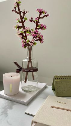 a vase filled with pink flowers sitting on top of a table next to a candle