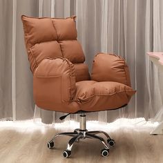 a brown chair sitting on top of a hard wood floor next to a pink desk