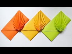 three origami pieces in different colors on a white surface