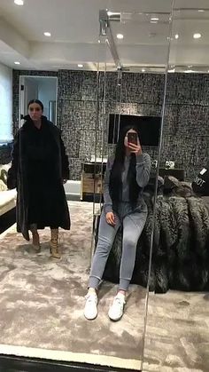 a woman taking a selfie in front of a mirror with another person behind her