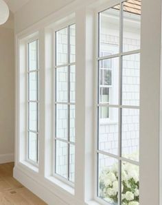 an empty room with three large windows and white flowers in the window sills