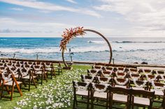 an outdoor ceremony set up with chairs and flowers on the grass by the ocean,