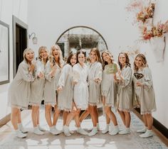 a group of women standing next to each other wearing robes and slip on shoes in front of a mirror