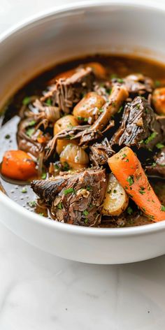 a white bowl filled with stew and carrots