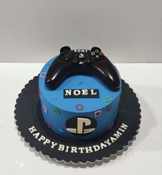 a blue birthday cake with a video game controller on it's top and the words noel happy birthday