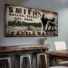 an old sign hangs on the wall above a table and bar stools in a dining room