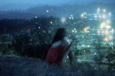 a woman sitting on top of a hill at night