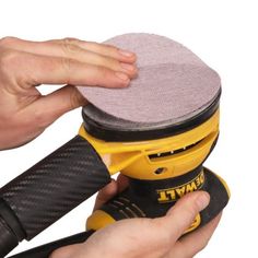 a person holding a sander in their right hand with the other hand on it