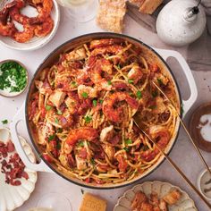 a pan filled with pasta and meat on top of a table next to other dishes