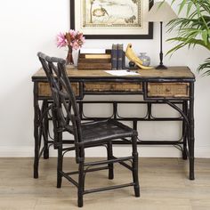 a desk with two chairs and a painting on the wall above it, in front of a plant