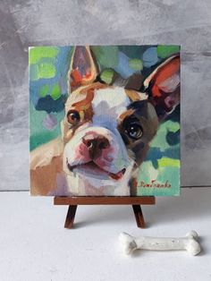 a painting of a brown and white dog on an easel next to a bone