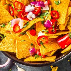 a bowl filled with nachos and toppings on top of a black table