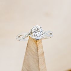 a diamond ring on top of a wooden stand