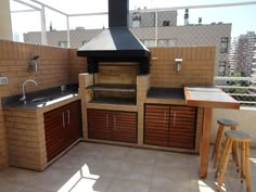 an outdoor kitchen on top of a roof with wooden cabinets and counter space for cooking