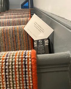 an orange and white striped rug on top of a gray stair case next to a sign