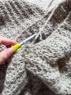 a person holding a crochet hook in their left hand and knitting the stitch