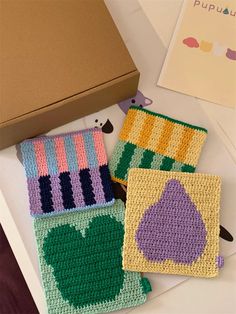 three crocheted coasters sitting on top of a table next to a box