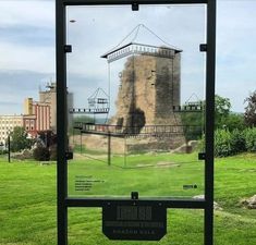 a sign in front of a grassy field with a tower on it's side