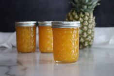 three jars filled with pineapple jam sitting on a counter