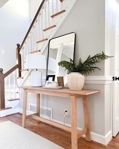 a wooden table sitting under a mirror next to a stair case