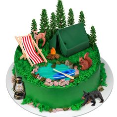 a cake decorated with lawn chairs and animals on top of green frosted grass next to a campfire