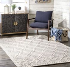 a living room area with a chair, rug and sideboard in it's corner