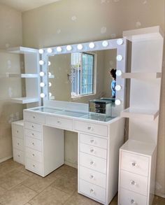 a white vanity with lighted lights and drawers