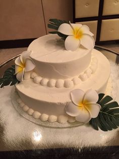 a three tiered cake with white frosting and flowers