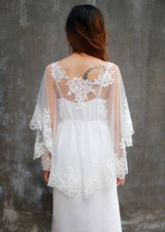 the back of a woman wearing a white wedding dress with sheer sleeves and lace detailing