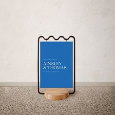 a blue sign sitting on top of a wooden stand in front of a white wall