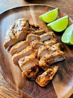 sliced chicken and limes on a wooden plate