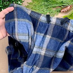 someone's hand is holding up the blue and gray flannel