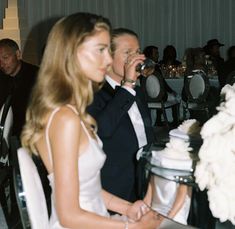 a man in a tuxedo sitting next to a woman at a table