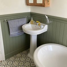 a white sink sitting under a mirror next to a bath tub in a room with green walls