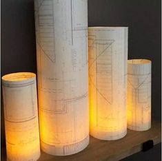 three paper lamps sitting on top of a wooden shelf next to each other, all lit up