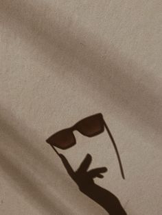 the shadow of a hand with sunglasses on it