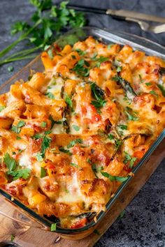 a casserole dish with chicken, cheese and parsley in it on a cutting board