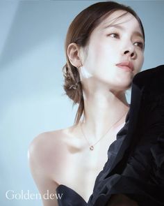 the woman is wearing a black dress and has a necklace on her left shoulder, while she's looking off to the side