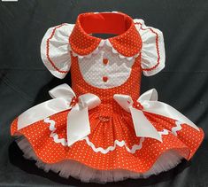 an orange and white polka dot dress with matching headband, collared shirt and bow tie