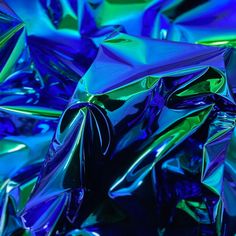 many shiny blue and green foils are piled on top of each other in this close up photo