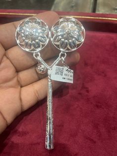 a pair of silver earrings sitting on top of a red velvet covered box with a price tag