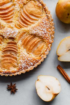 an apple pie with sliced apples and cinnamon on the side, surrounded by other ingredients