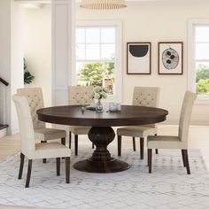 a dining room table with four chairs and a rug on the floor in front of it