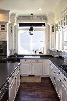 a kitchen with white cabinets and black counter tops