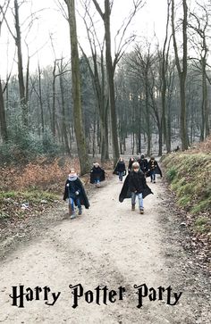 some kids are walking down a dirt road in the woods with coats on and capes over their heads