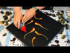 a woman is cutting into a piece of art on a table with black and yellow paint