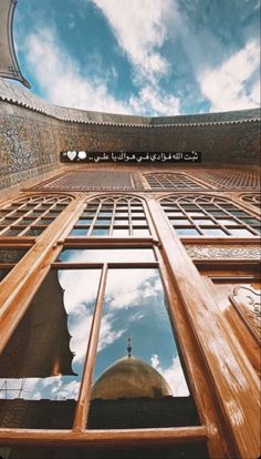 the reflection of an islamic building in a window with sky and clouds reflected on it