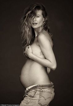 a pregnant woman posing for a black and white photo with her hands on her hips